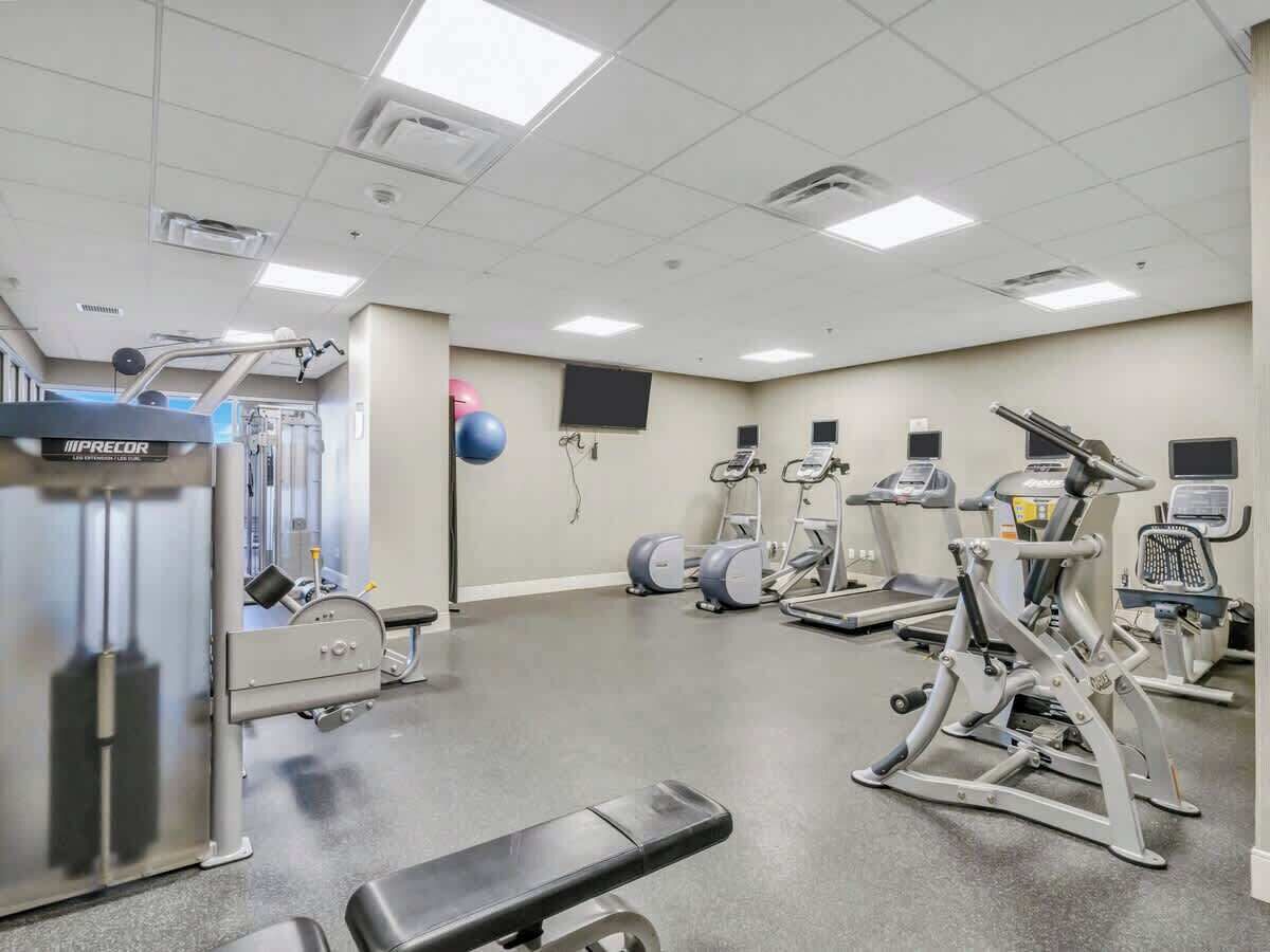 A gym with various exercise equipment, including a treadmill, elliptical, and weight machines.