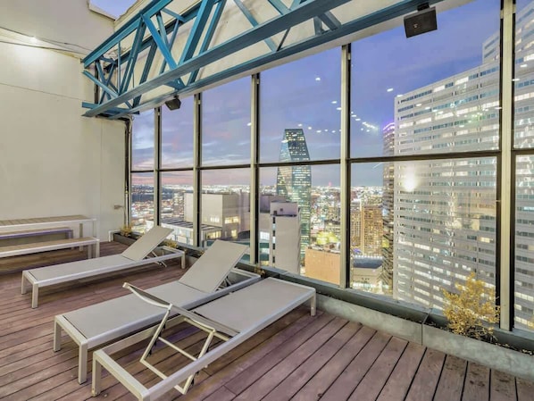 Eine Dachterrasse mit Liegestühlen und Blick auf die Stadt.