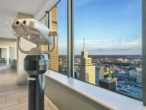 Ein modernes Zimmer mit großem Fenster und Blick auf die Stadt, darunter ein markanter Turm.