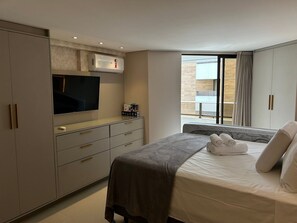 Ein Hotelzimmer mit Bett, Fernseher, Minibar und einem Fenster mit Blick.