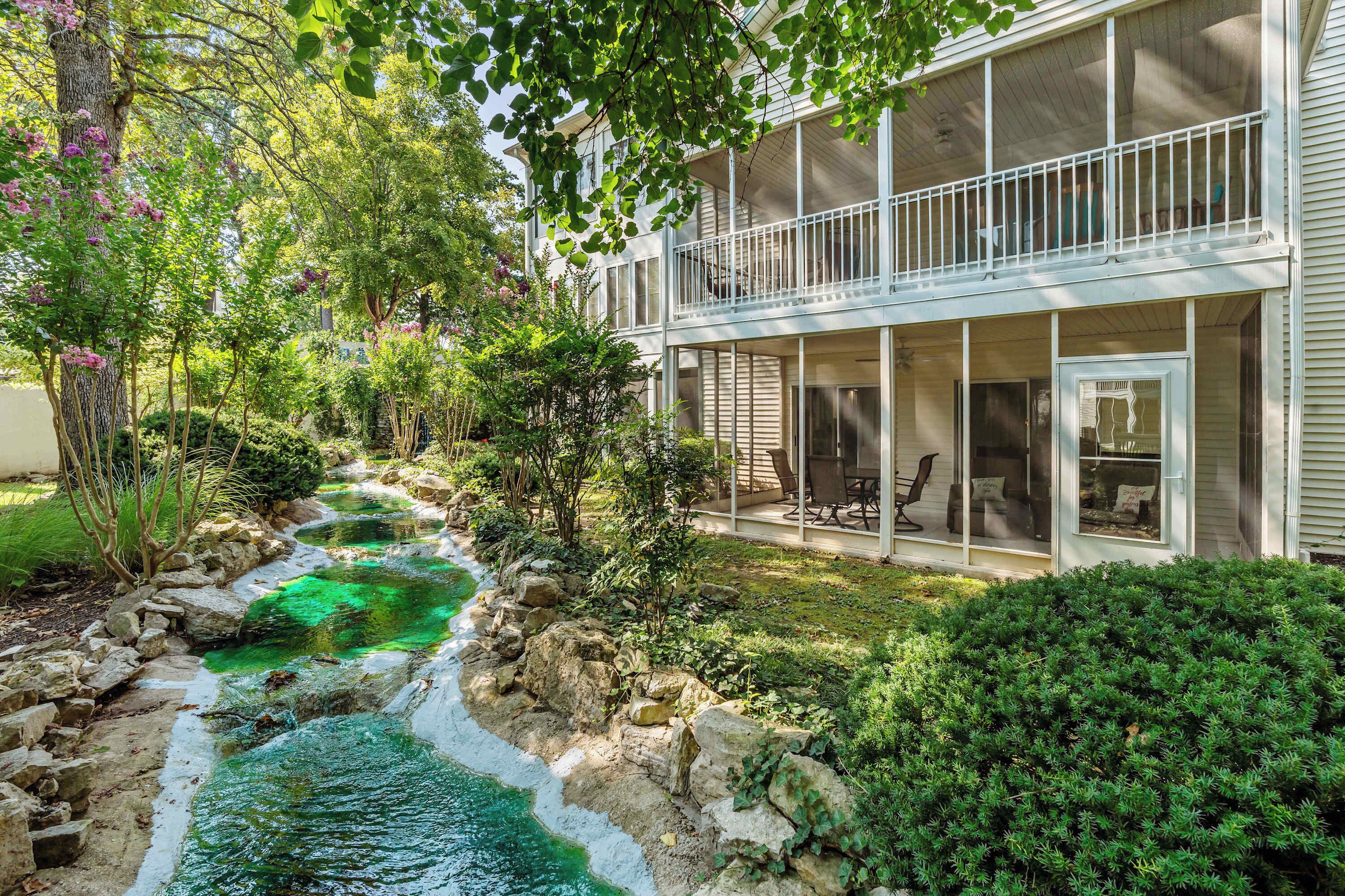 A two-story building with a covered outdoor seating area and a small stream running through the garden.