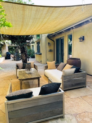 Ein möblierter Patio mit einer Couch, Sesseln, einem Tisch und einem dekorativen Topf.