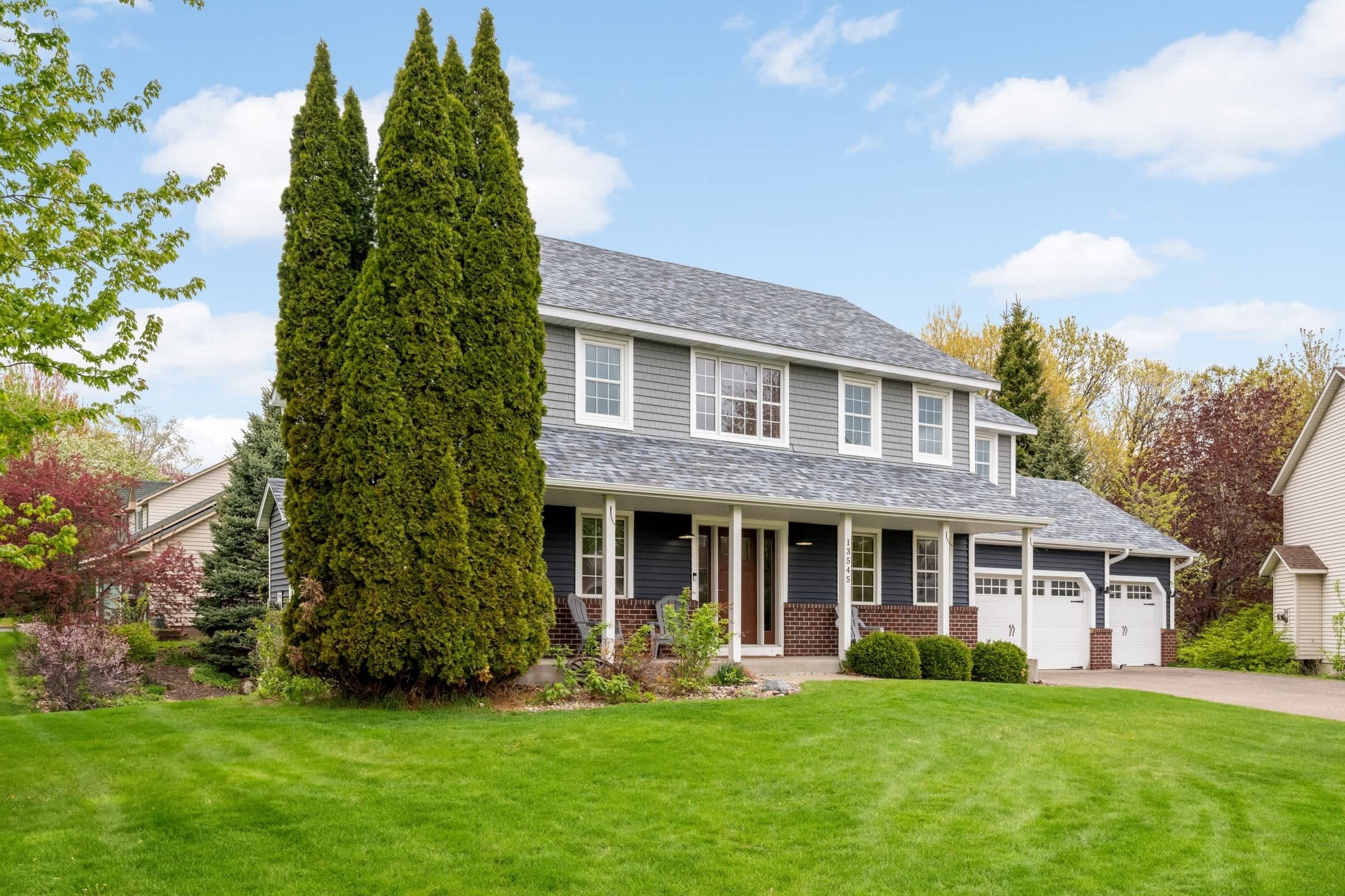 A two-story house with a covered porch, a garage, and a well-maintained lawn.