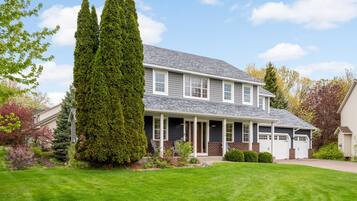 A two-story house with a covered porch, a garage, and a well-maintained lawn.