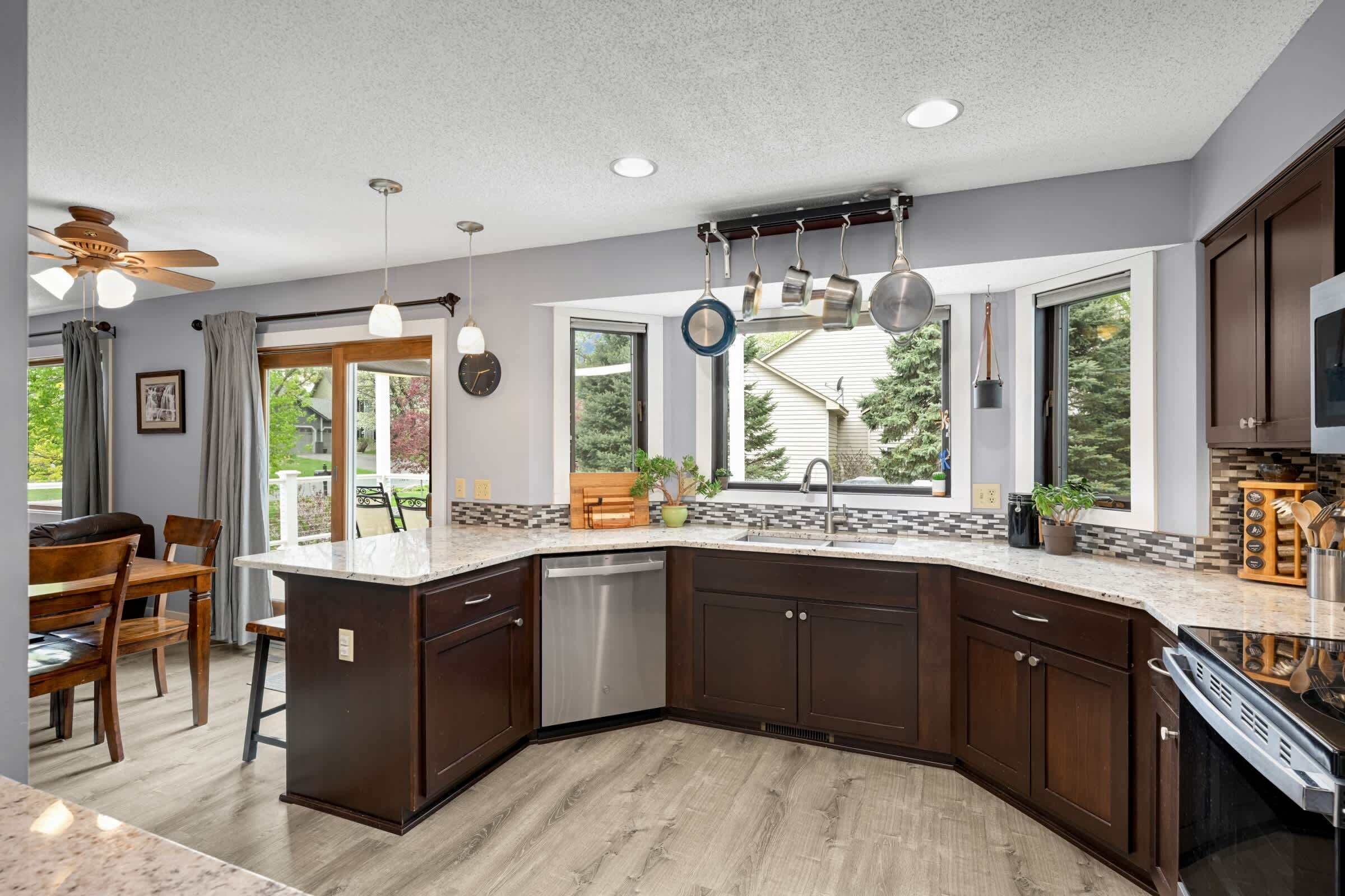 A modern kitchen with dark wood cabinets, a built-in dishwasher, and a large island with a sink.