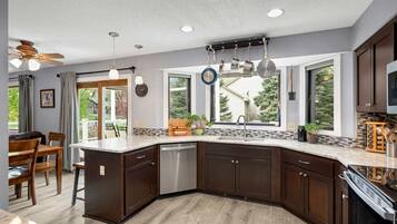 A modern kitchen with dark wood cabinets, a built-in dishwasher, and a large island with a sink.