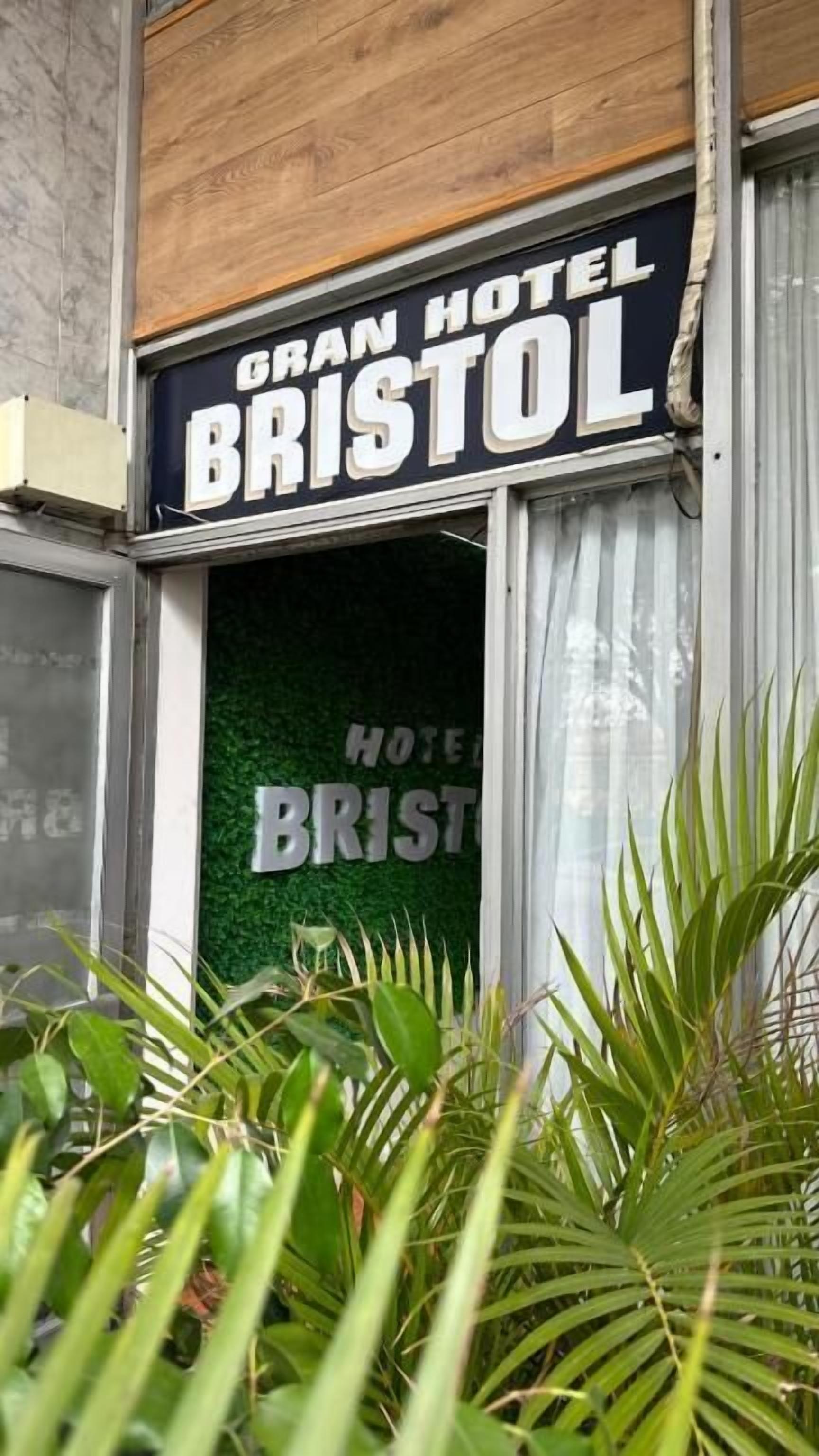 The Gran Hotel Bristol sign, a green window with the hotel's name, and a wooden facade.