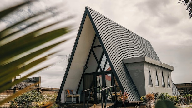 A modern house with a triangular roof, surrounded by a grassy area and a palm tree. - Eco-friendly A-frame Cabin 10min to Nungwispacious A-frame Retreat Cabin in Zanz (Nungwi)