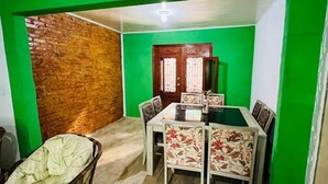 A dining area with a wooden table and chairs, a green wall, and a brick wall. - Complete country house for weekends and events. (Itaquaquecetuba)
