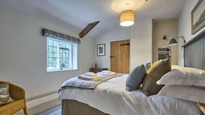 Un dormitorio con cama, ventana, puerta, silla y lámpara colgante.