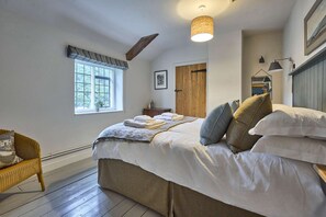 Ein Schlafzimmer mit Bett, Fenster, Tür, Stuhl und einer Pendelleuchte.