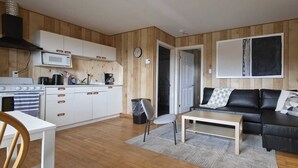 Un espacio habitable compacto con kitchenette, un sofá, una mesa de centro y una zona de comedor.