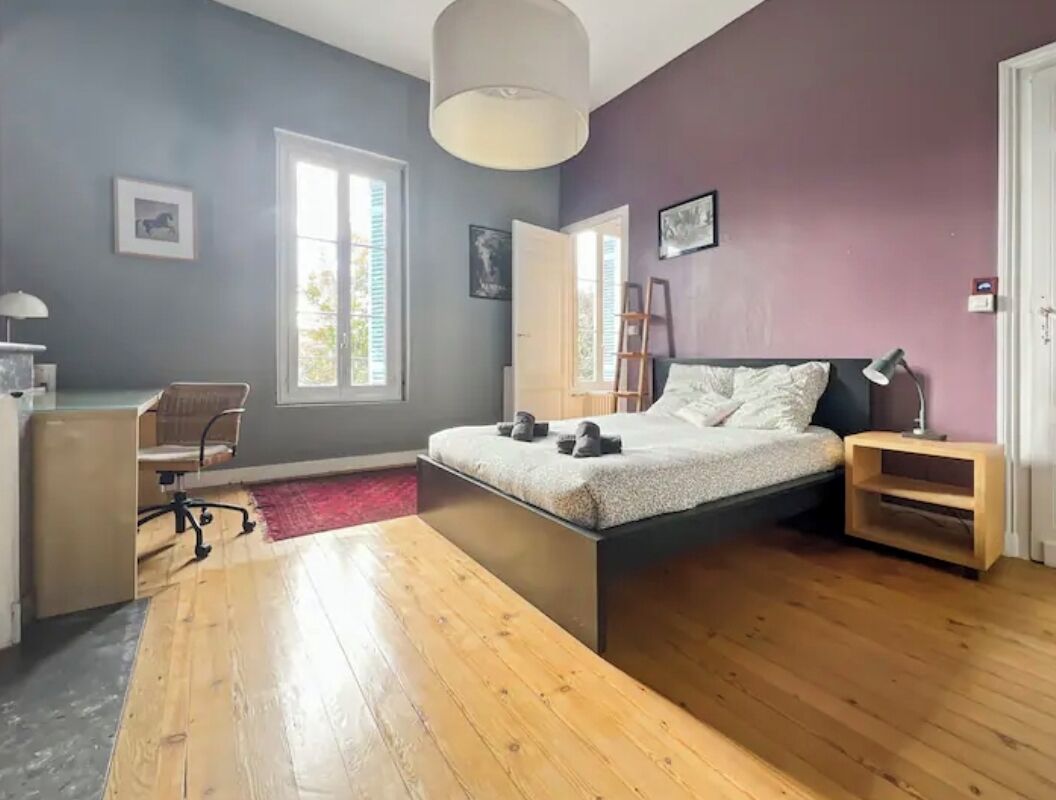 A bedroom with a bed, a desk, a chair, a ladder, and a window.