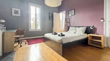 A bedroom with a bed, a desk, a chair, a ladder, and a window.