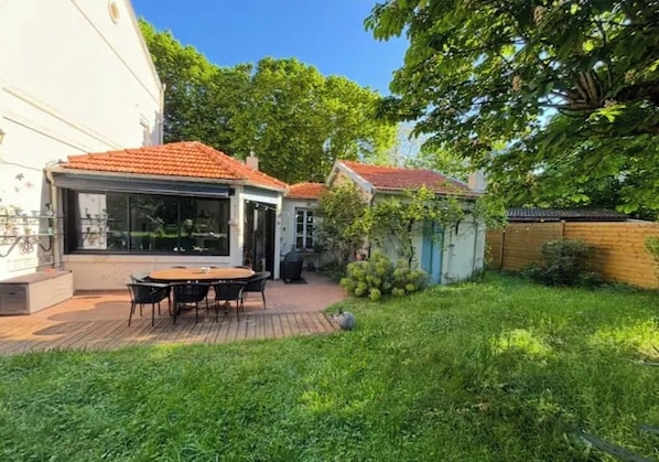 A backyard with a wooden deck, a table with chairs, and a small garden area.