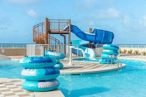 Ein Pool mit Wasserrutsche, Luftreifen und einer Holzkonstruktion.