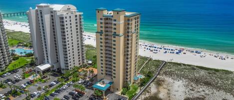 A high-rise hotel with a pool and beach access, located near a pier.