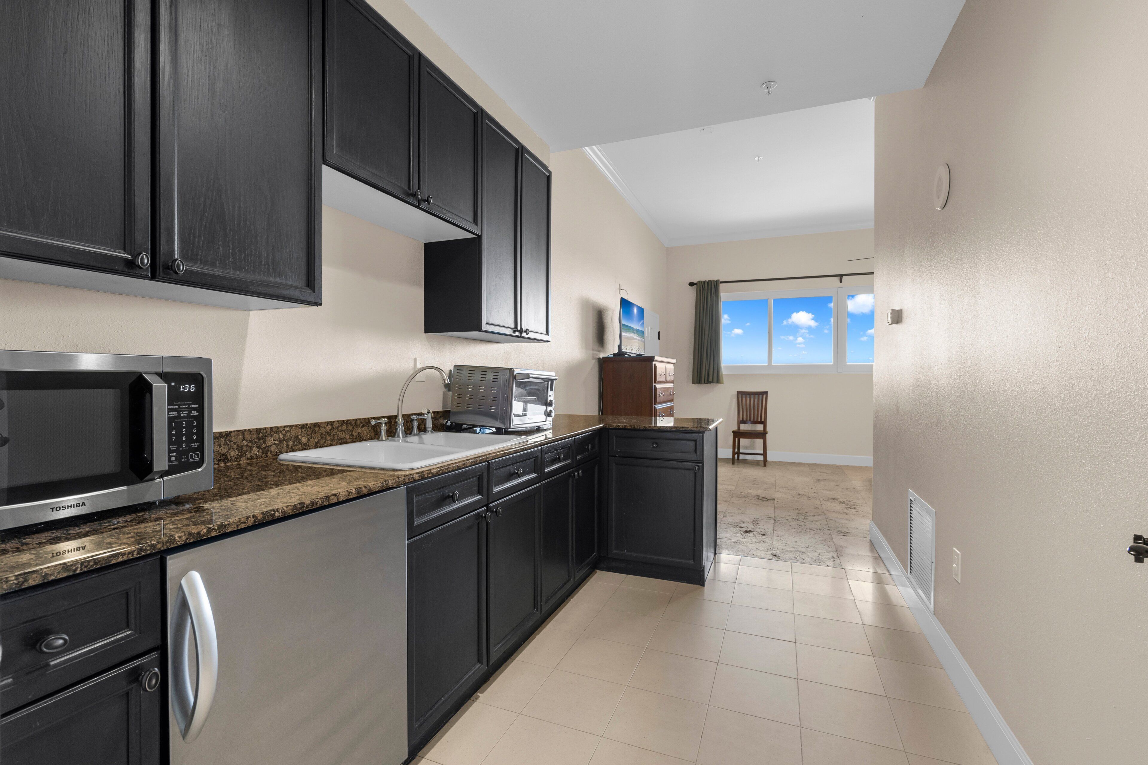 A modern kitchen with dark cabinetry, a microwave, a toaster, and a sink.