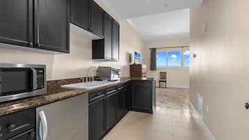 A modern kitchen with dark cabinetry, a microwave, a toaster, and a sink.