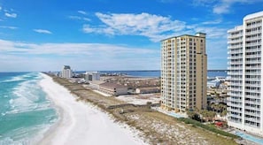 Ein Küstenhotel mit Blick auf den Strand, mehreren Etagen und einem Poolbereich.