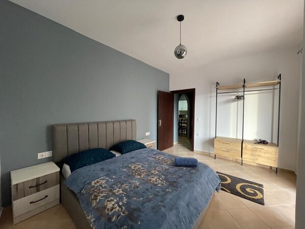 A bedroom with a bed, bedside table, and a wardrobe. - Skapeta Apartments (Saranda)