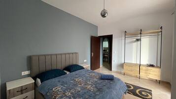 Une chambre à coucher avec un lit, des tables de chevet, une armoire et un luminaire au plafond.