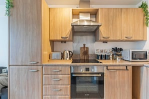 Eine moderne Küche mit Holzschränken, einem Backofen von Bosch, einer Mikrowelle und einer Kaffeemaschine.