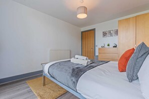 Ein modernes Schlafzimmer mit einem Bett, einem Holzschrank, einem Heizkörper und einer kleinen Pflanze auf dem Nachttisch.