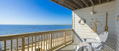 A wooden deck with a view of the ocean, a lifebuoy, and a paddleboard.