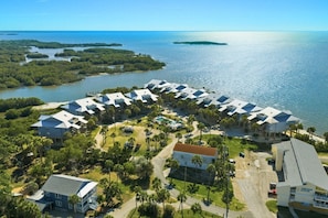 A resort with a circular building layout, surrounded by palm trees and a beach.