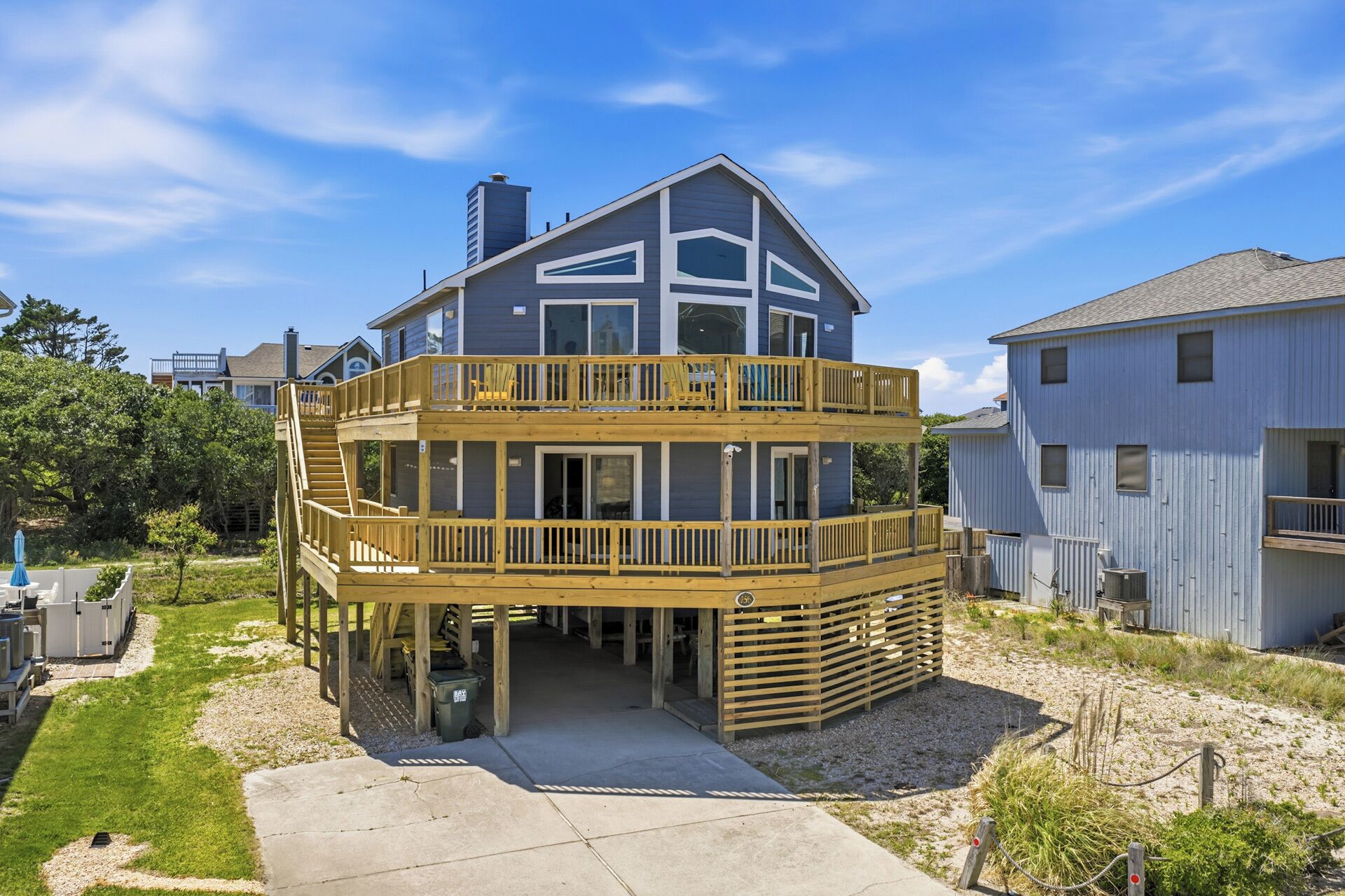 A two-story house with a wooden deck and a covered area.