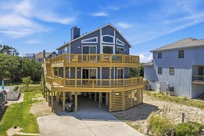 Een tweelaags huis met een houten terras en een overdekt gedeelte.