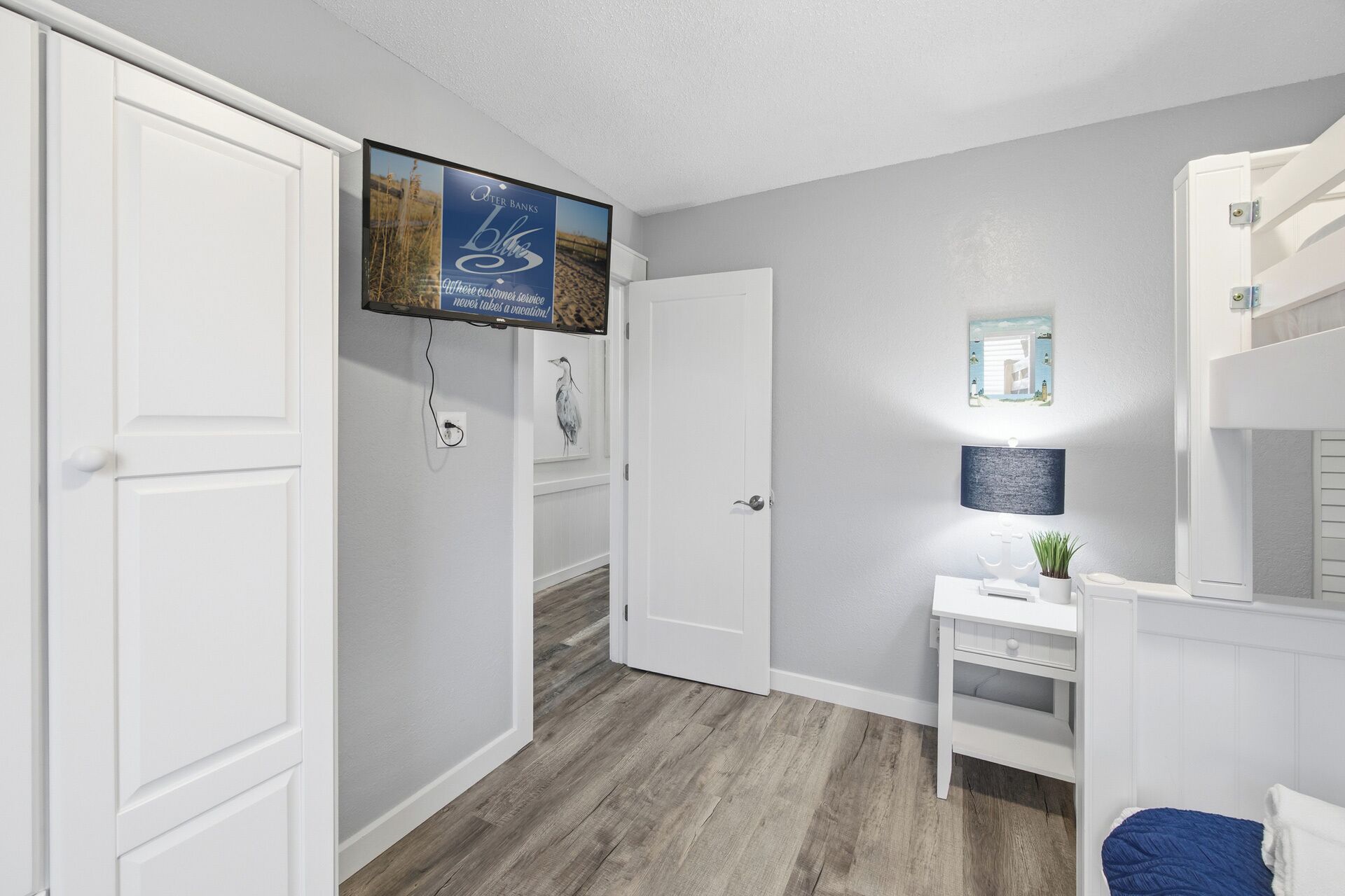 A hallway with white doors, a desk with a lamp, and a bunk bed.