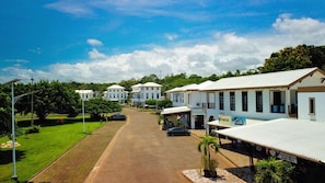 A row of white colonial-style buildings with a paved road in front, surrounded by greenery. - House with Private Pool in Playa Bejuco (Parrita)