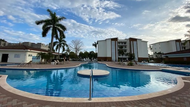 A swimming pool with a palm tree, lounge chairs, and a clear sky. - House with Private Pool in Playa Bejuco (Parrita)