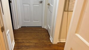 A hallway with wooden flooring and white doors.