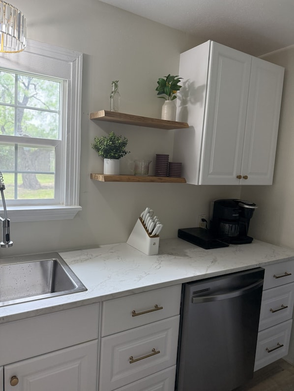 A kitchen with white cabinets, a coffee maker, and a dishwasher.