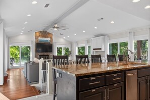 A spacious kitchen with a granite countertop, dark cabinetry, and a ceiling fan.