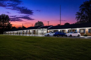 A motel with a row of rooms, a parking lot, and a clear sky. - Siler City Motor Lodge (Siler City)