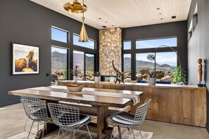 Una cocina moderna con una isla grande, pared de acento de piedra y ventanas amplias con vistas al paisaje desértico.