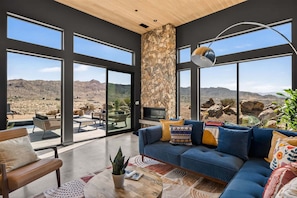 Una sala de estar moderna con una pared de piedra, ventanas amplias y vistas al paisaje desértico.
