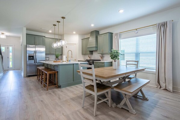 A modern kitchen with a central island, bar stools, and pendant lighting.