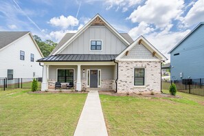 A two-story house with a front porch, a small brick section, and a clear sky.