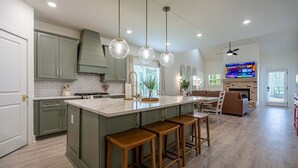 A spacious kitchen with a large island, bar stools, and a dining area with a TV. - Pet-Friendly 4BR 5 Min to LakePoint with TV Room (Emerson)