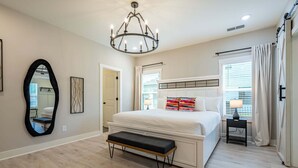 A bedroom with a bed, bench, chandelier, and a large mirror. - Pet-Friendly 4BR 5 Min to LakePoint with TV Room (Emerson)