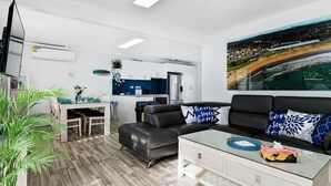 En moderne stue med sofa, sofabord og et spiseområde med stole og bord.