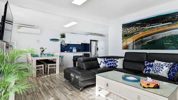 Una sala de estar moderna con un sofá, una mesa de centro de vidrio y un comedor con una mesa y sillas.