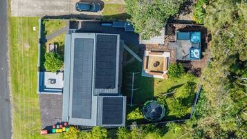 A residential property with a large house, solar panels, a swimming pool, and a trampoline.