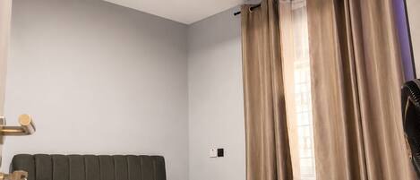 A modern bedroom with a bed, curtains, and a ceiling light.