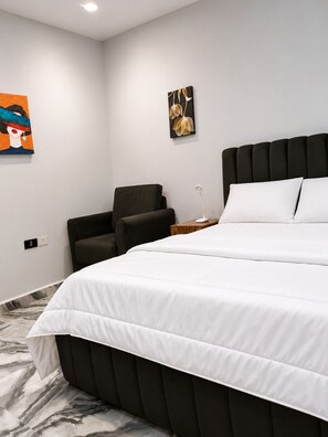 Un dormitorio moderno con una cama grande, una silla y dos obras de arte en la pared.